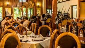 A restaurant with wooden interiors and tables set for dining. - El Rodeo Estancia Boutique Hotel & Steakhouse (San Rafael)