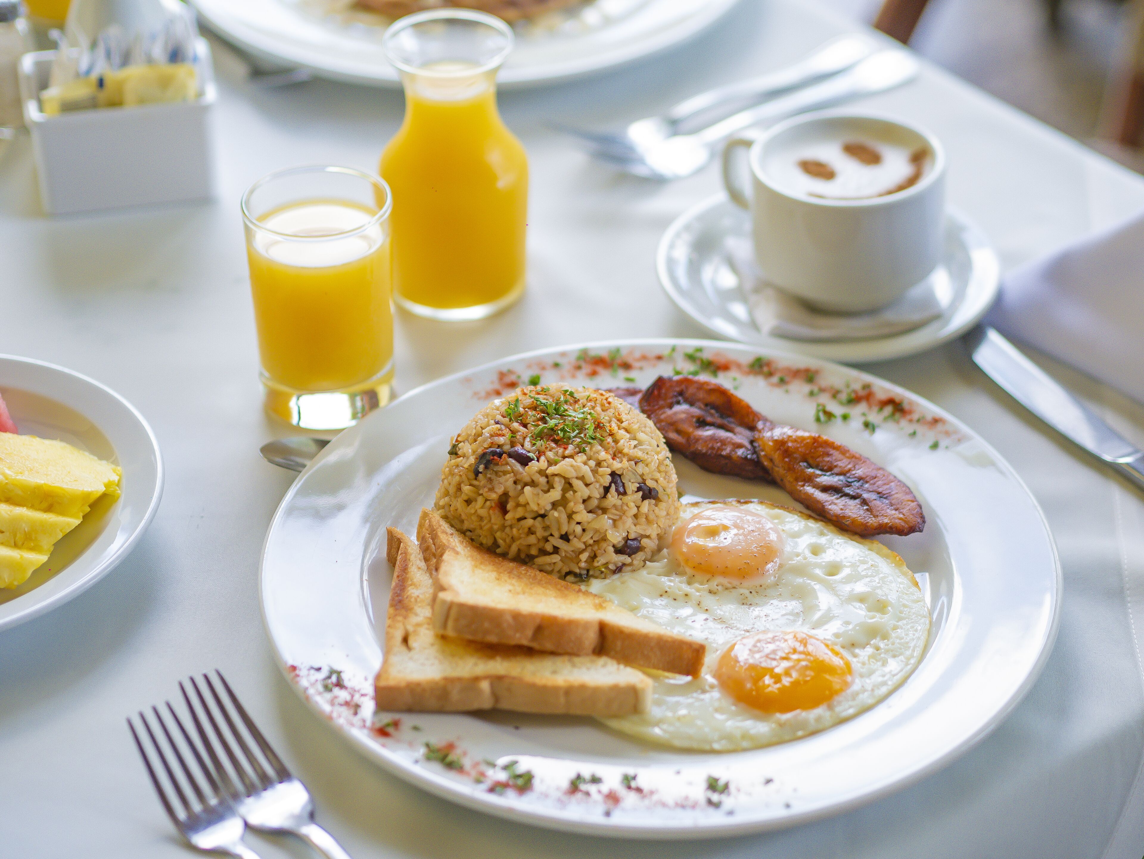 A breakfast plate with fried rice, eggs, toast, and bacon.