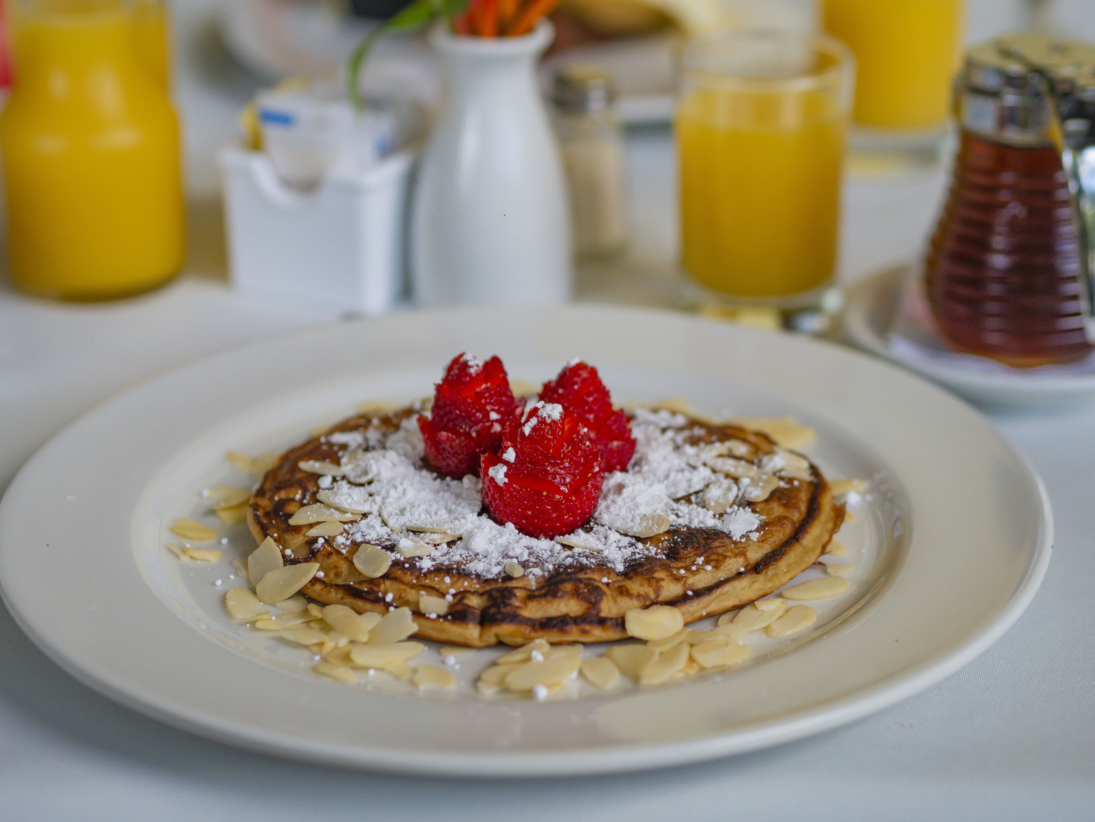 A plate of pancakes with strawberries and almonds.