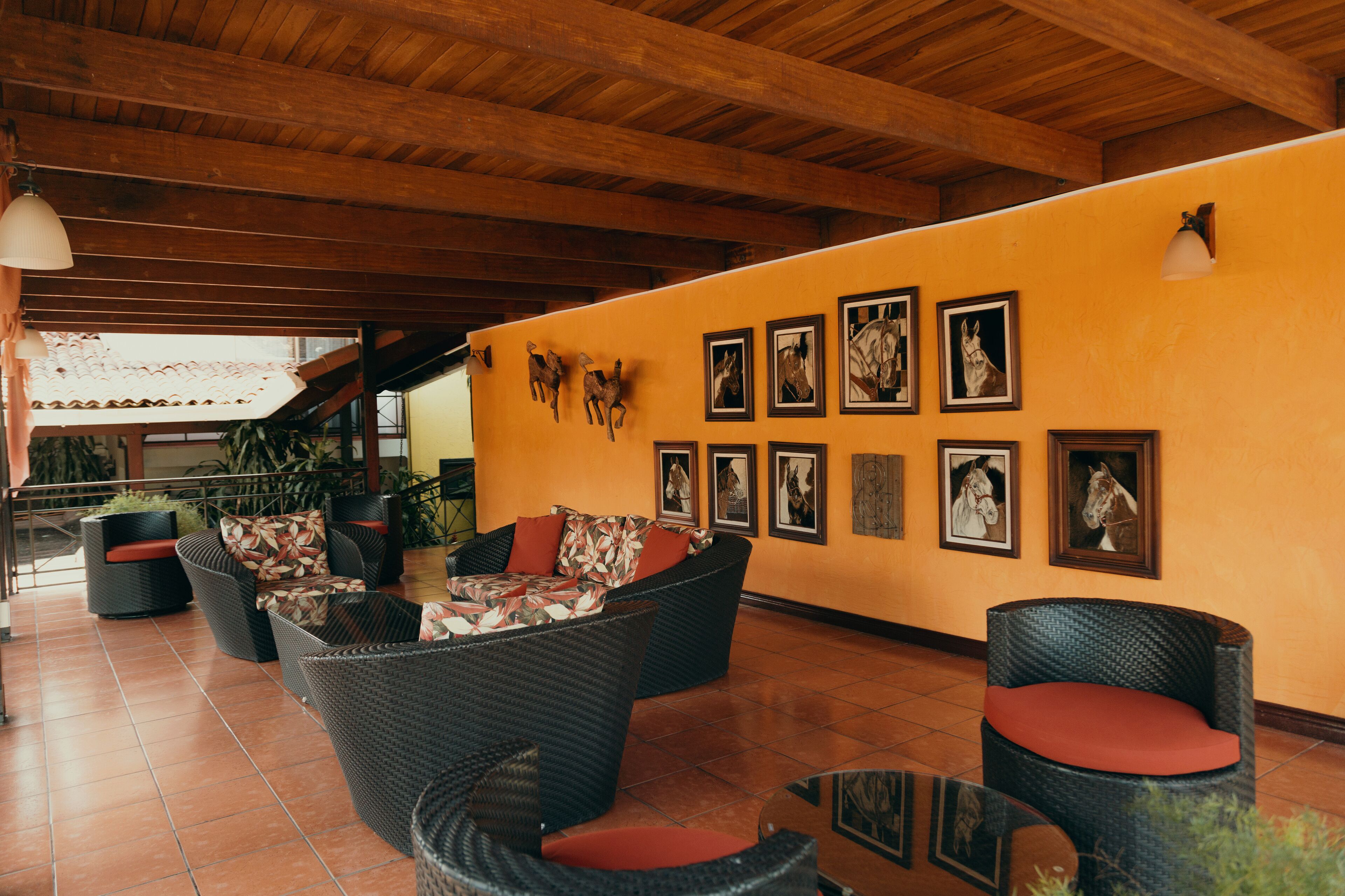 A lobby with wicker furniture, a tiled floor, and a wall adorned with framed pictures.