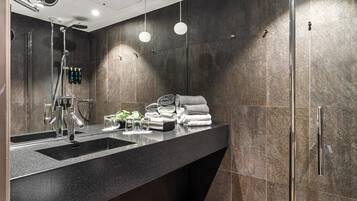 Une salle de bain moderne avec un plan de toilette noir, deux vasques, une douche et un porte-serviettes.