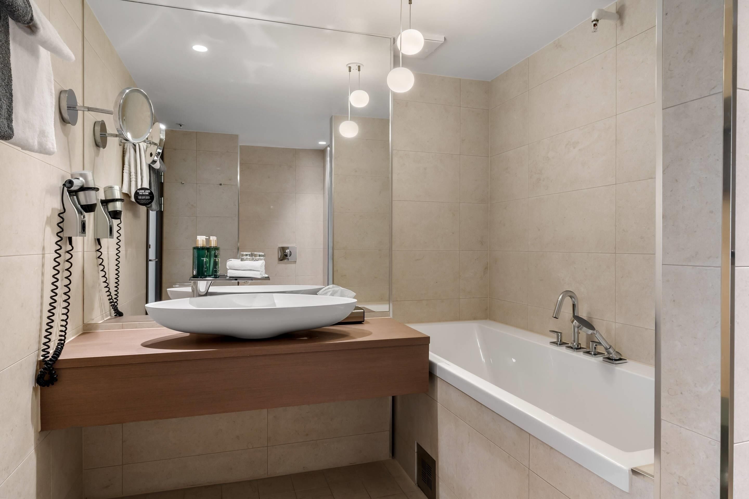 A modern bathroom with a large sink, a bathtub, and a mirror.