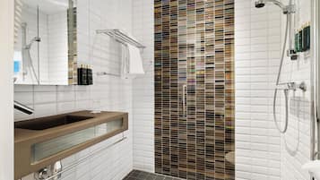 A modern bathroom with a glass-enclosed vanity, a shower with a glass partition, and a mirror with a towel rack.