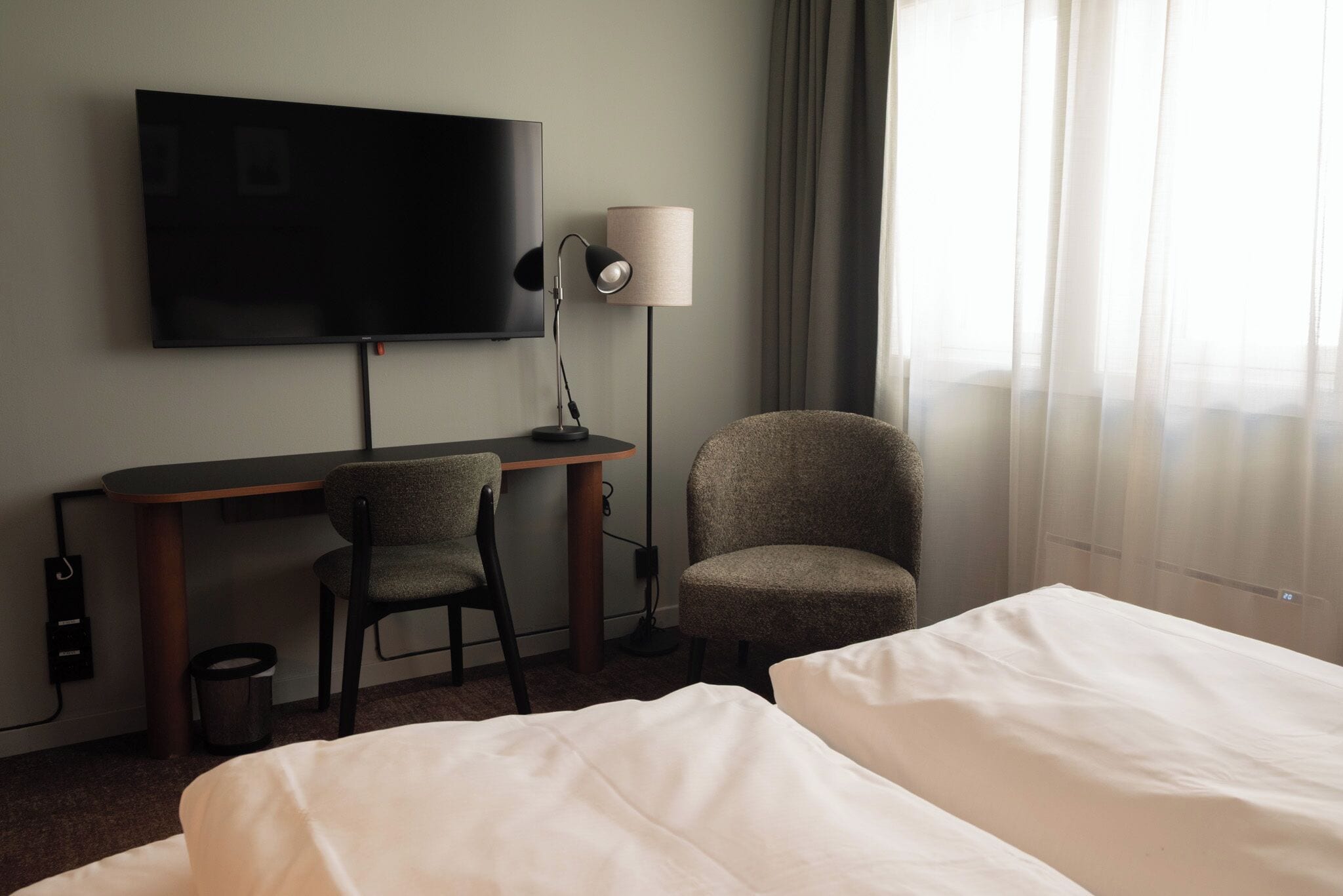 Ein Hotelzimmer mit Bett, Schreibtisch, Stuhl, Fernseher und Lampe.