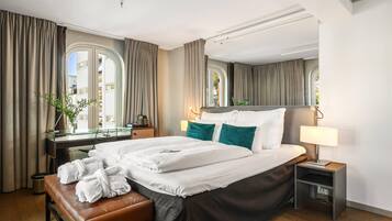 A hotel room with a large bed, a desk, and a bench.