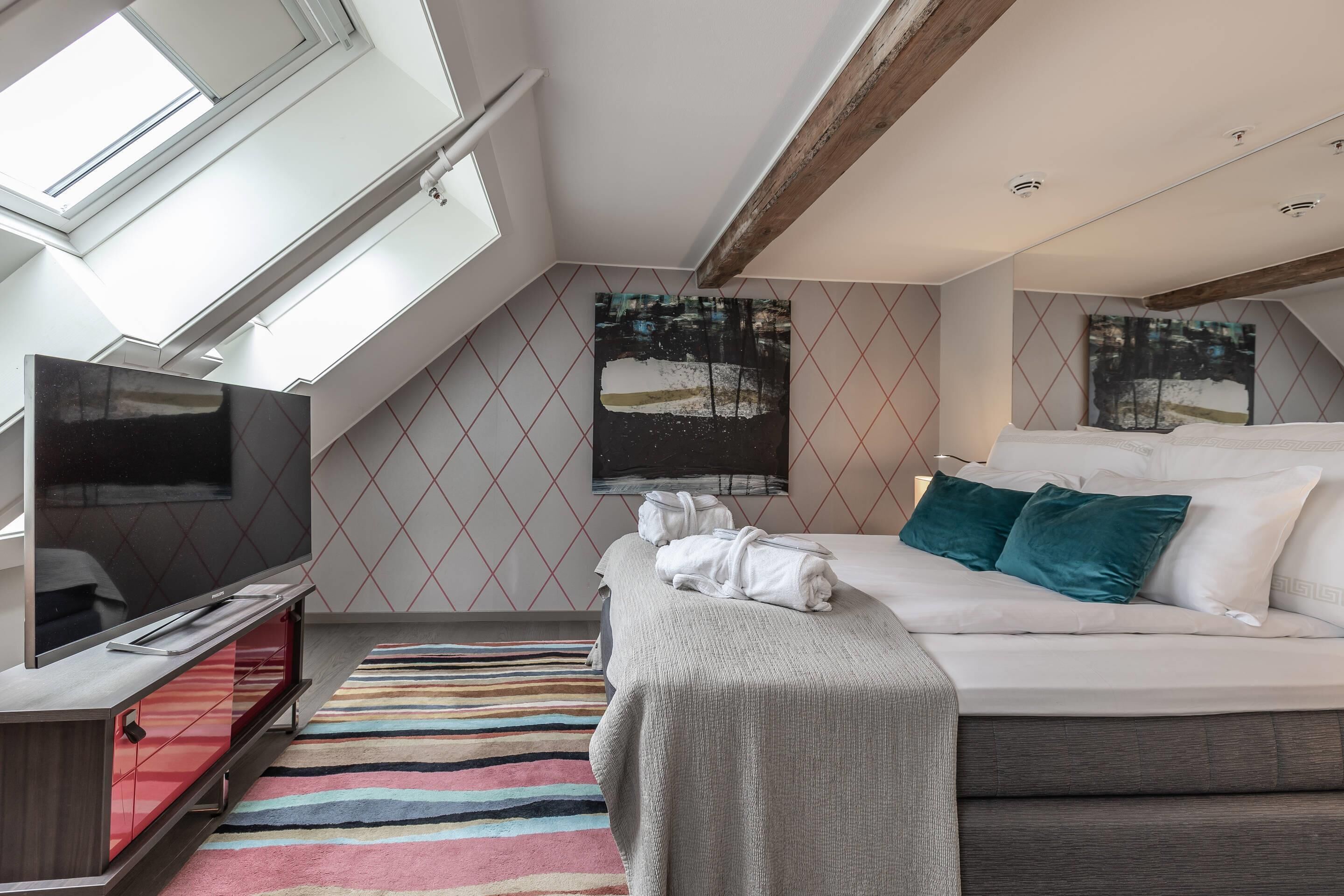 Una camera d'albergo moderna con un letto grande, una TV a schermo piatto e un lucernario.