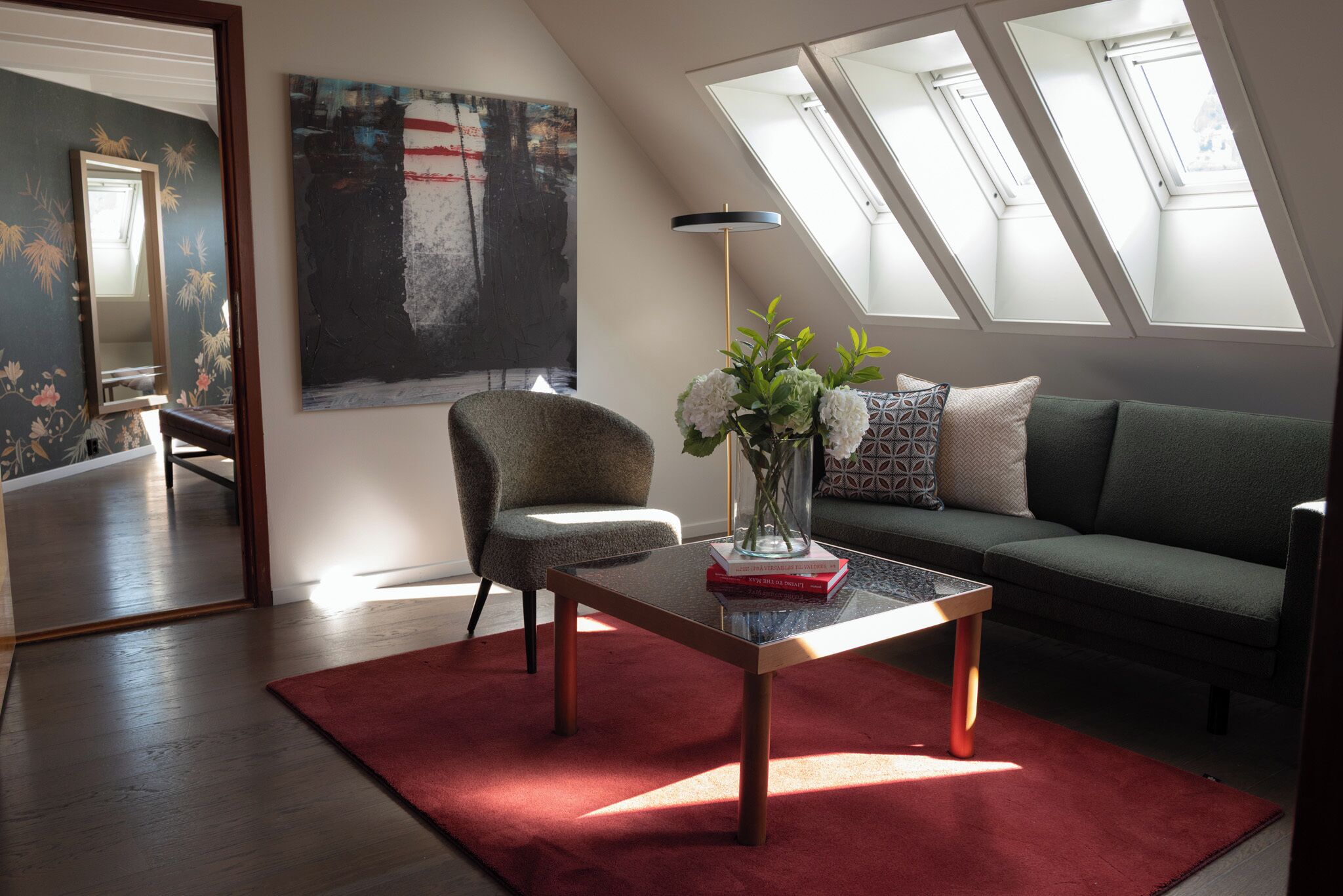 A modern living room with a sofa, armchair, and a coffee table with a vase of flowers.