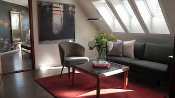 A modern living room with a sofa, armchair, and a coffee table with a vase of flowers.
