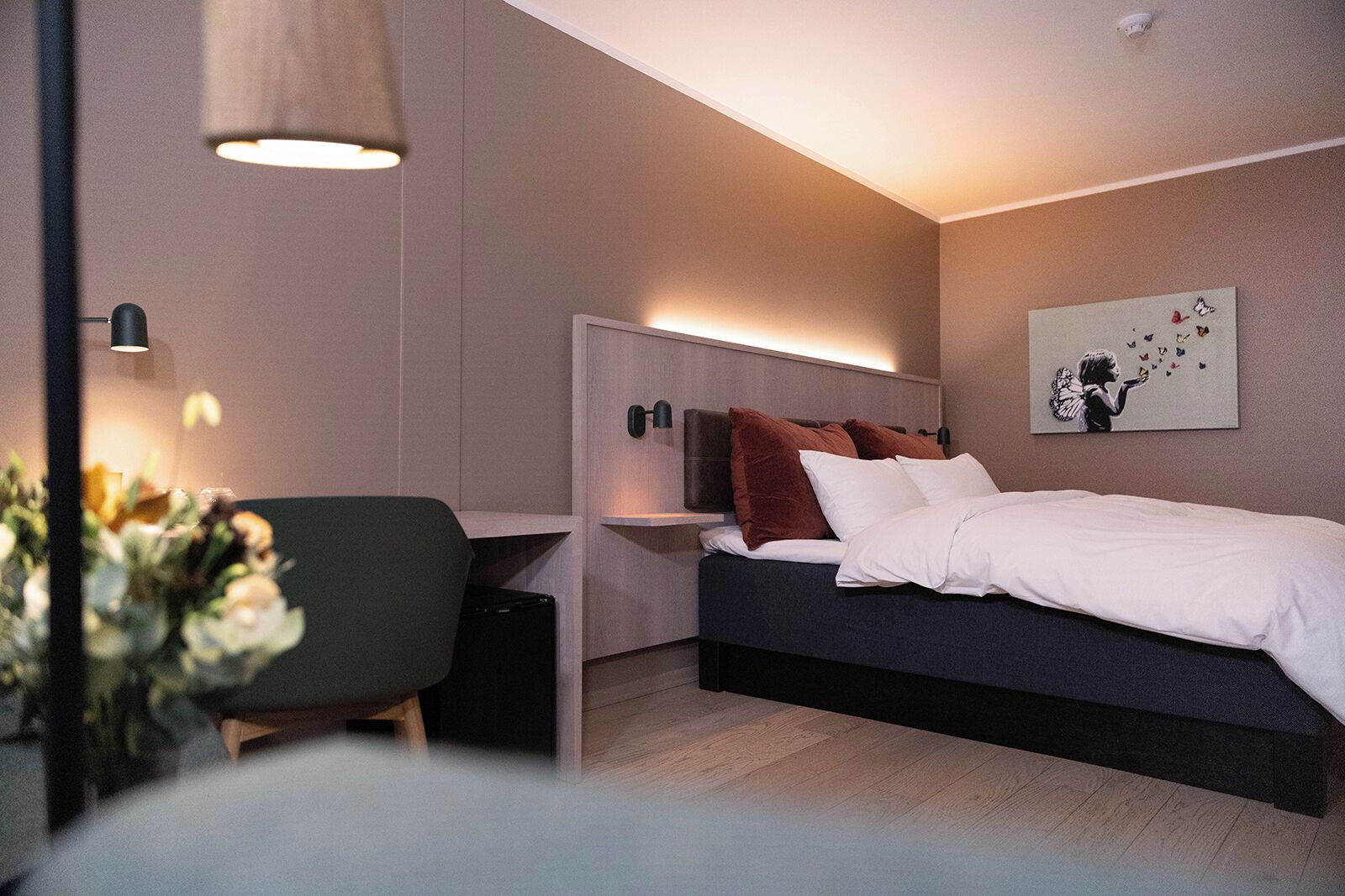 A modern bedroom with a bed, bedside tables, a desk, and a chair.