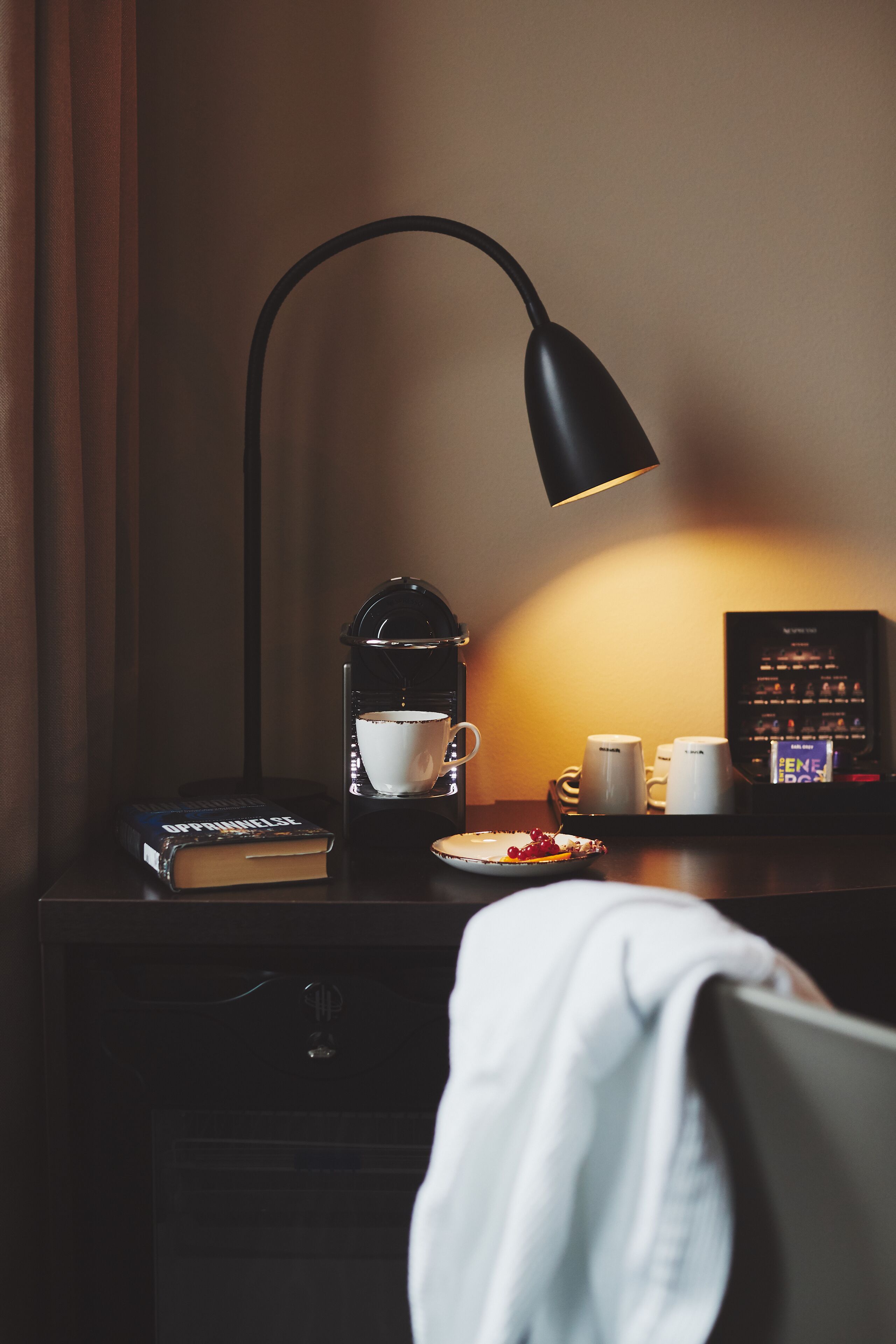 Een bureau met een koffiezetapparaat, een kop, een boek en zakdoeken.