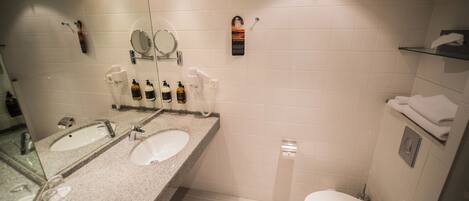 Un baño moderno con dos lavabos, un inodoro y una zona de ducha.