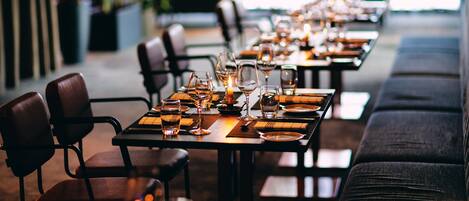 Un restaurante con mesas largas dispuestas para comer, sillas y velas.