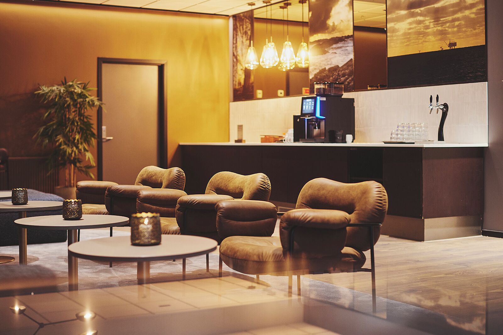 A modern lobby with leather armchairs, a reception desk, and a large wall-mounted TV.