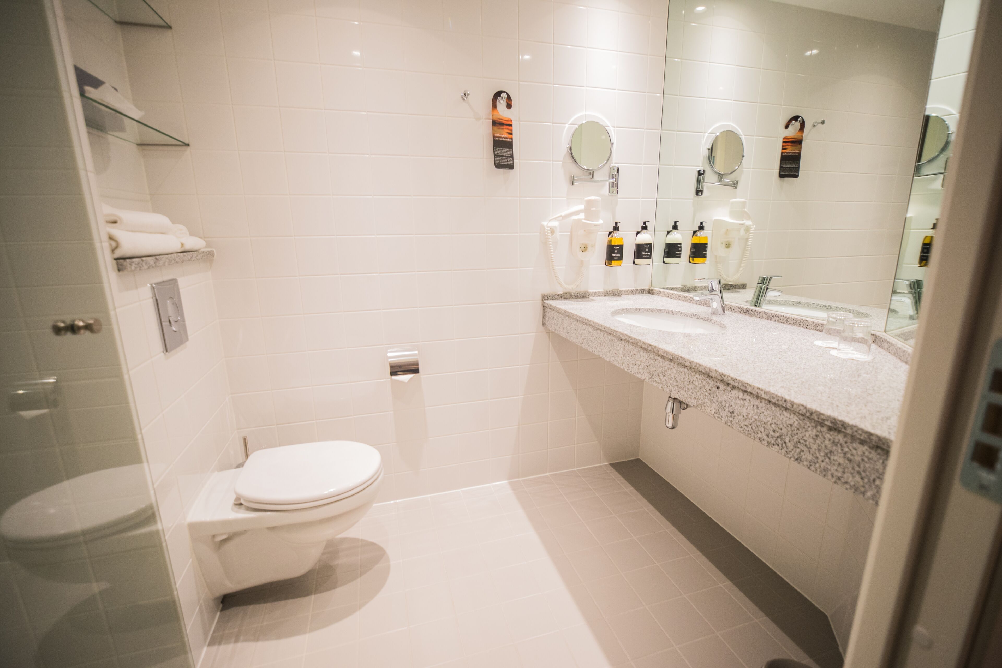 A modern bathroom with a toilet, sink, and glass shower enclosure.