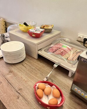 Enjoy a hearty breakfast at your table with a selection of eggs, meats, and utensils.