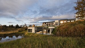 A modern house with a large glass facade, a small outdoor kitchen, and a pond in the foreground. - Roros Hotell (Roros)