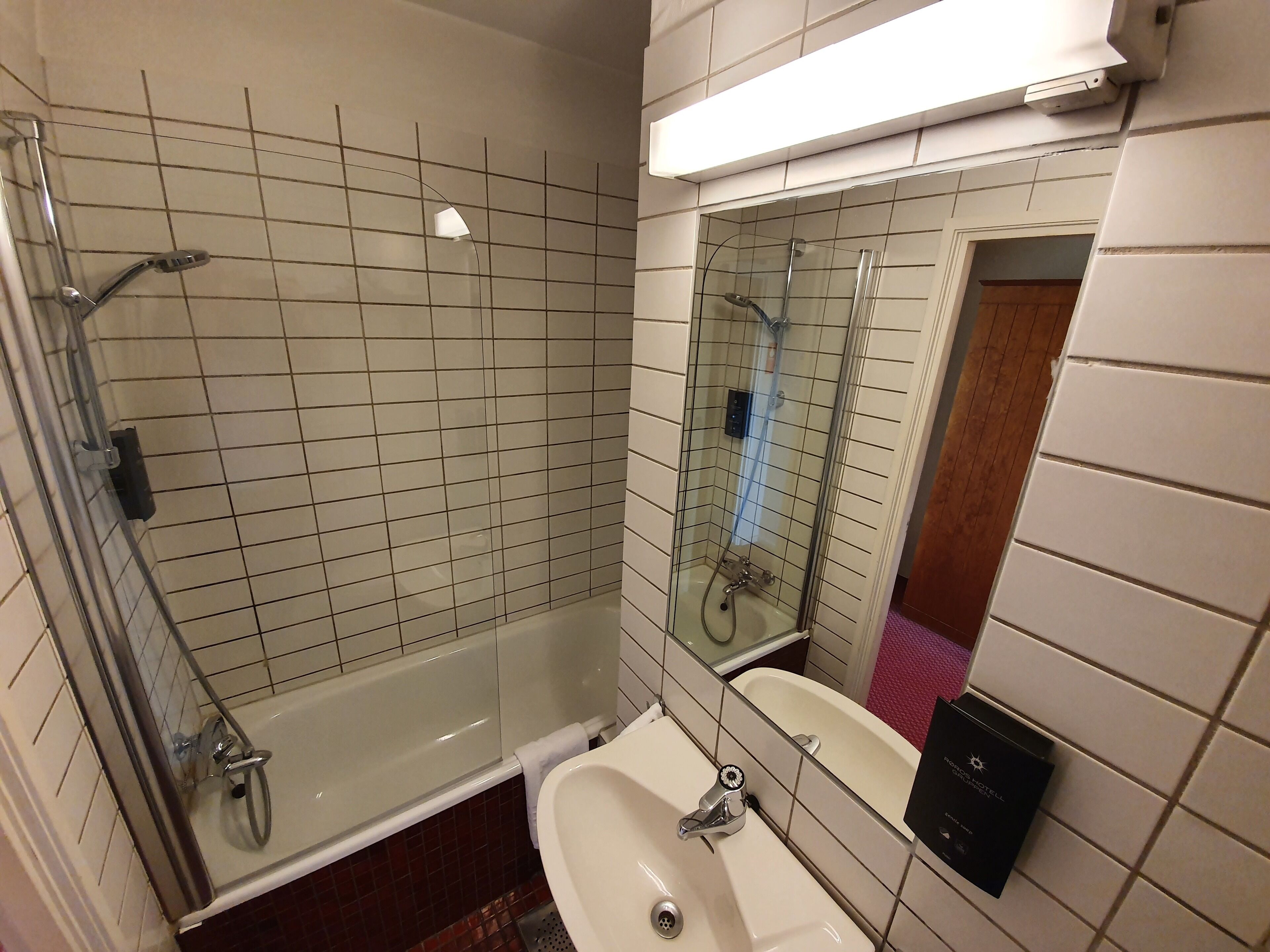 Un baño con ducha de vidrio, un lavabo blanco y un espejo.