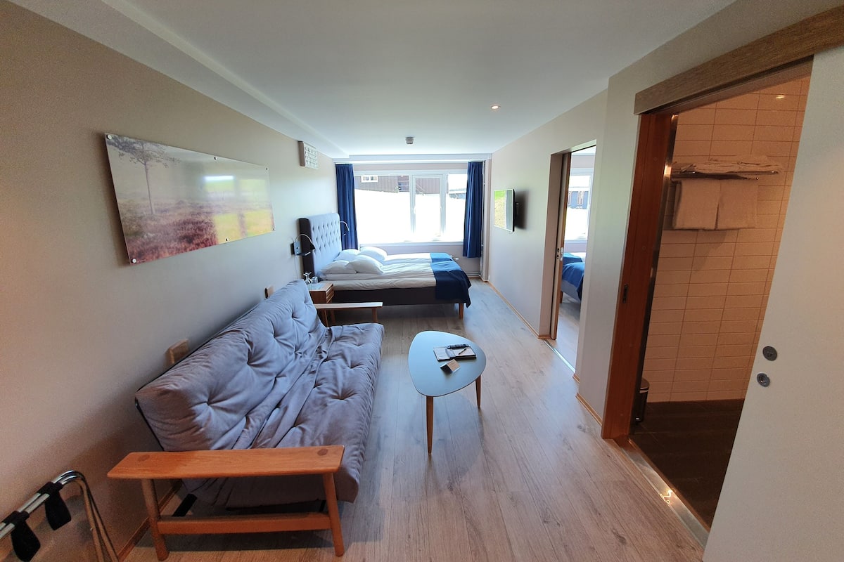 Ein modernes Hotelzimmer mit einer Couch, einem kleinen Tisch und einem Bett.