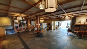 A spacious lobby with a stone floor, wooden beams, and hanging lamps. - Roros Hotell (Roros)