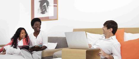 Ein Hotelzimmer mit einem Bett, einem Laptop und einer Person, die ein Tablet benutzt.
