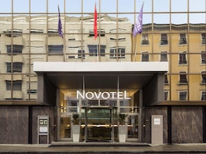A hotel entrance with a glass facade, a sign reading 'Novotel,' and a revolving door. - Novotel Geneve Centre (Geneva)