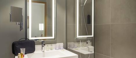 A modern bathroom with a vanity, two mirrors, a shower, and a towel rack.