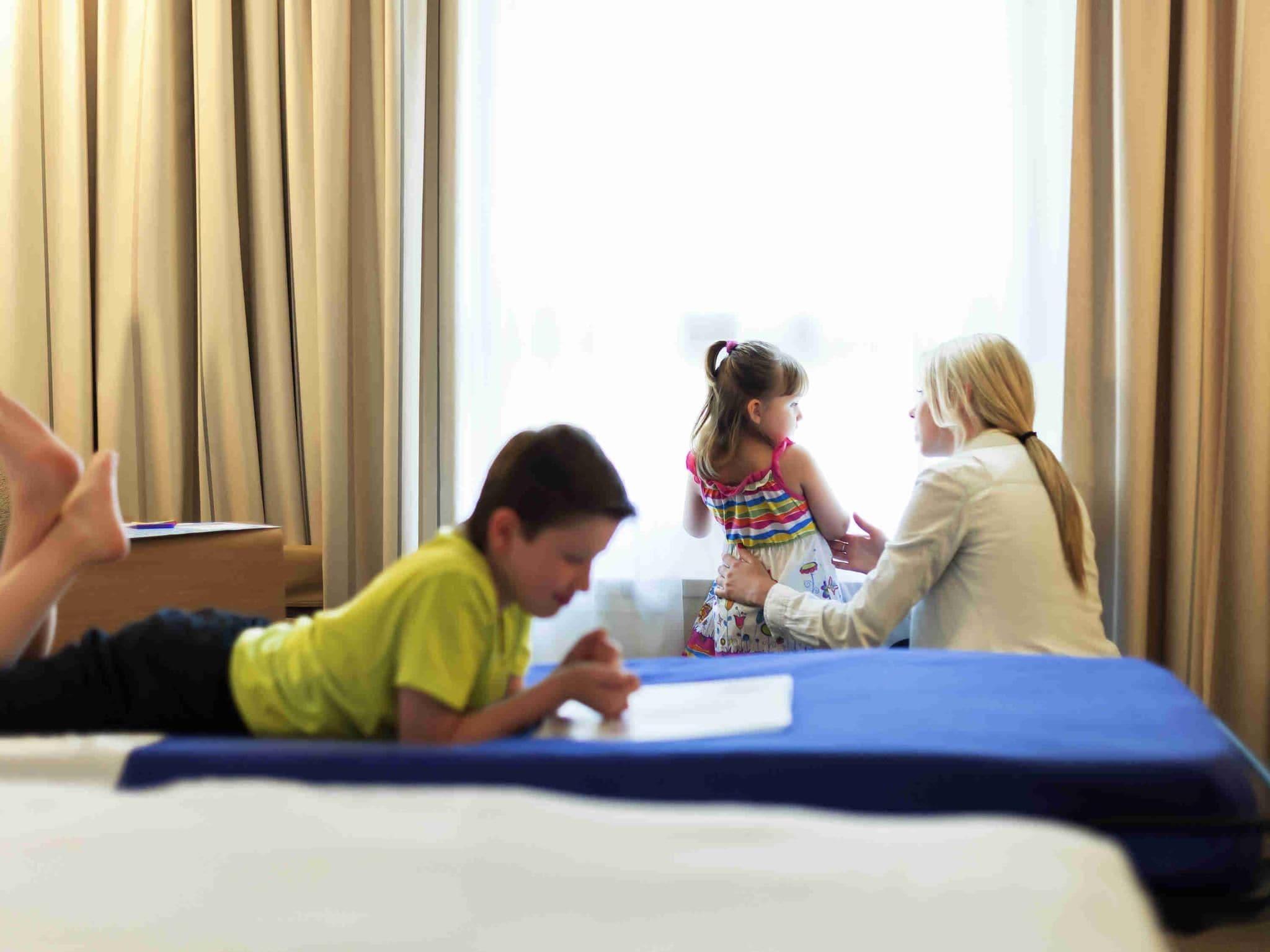 Una habitación de hotel con una cama, un escritorio y una ventana con cortinas.