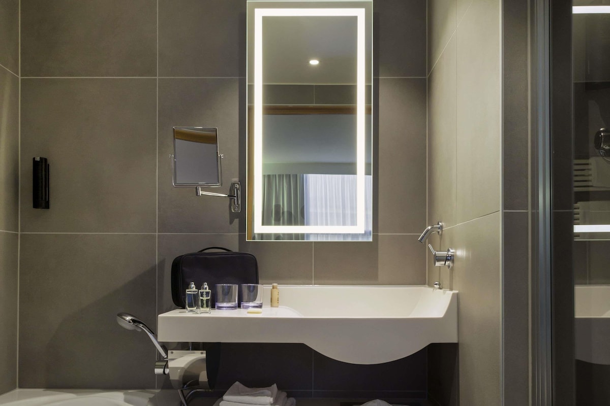 Une salle de bain moderne avec un grand miroir, un lavabo et un espace douche.