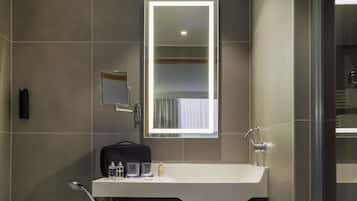 A modern bathroom with a large mirror, a sink, and a shower area.
