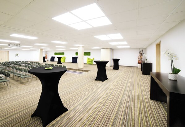 Un salón de conferencias con varias mesas, sillas y un escenario.