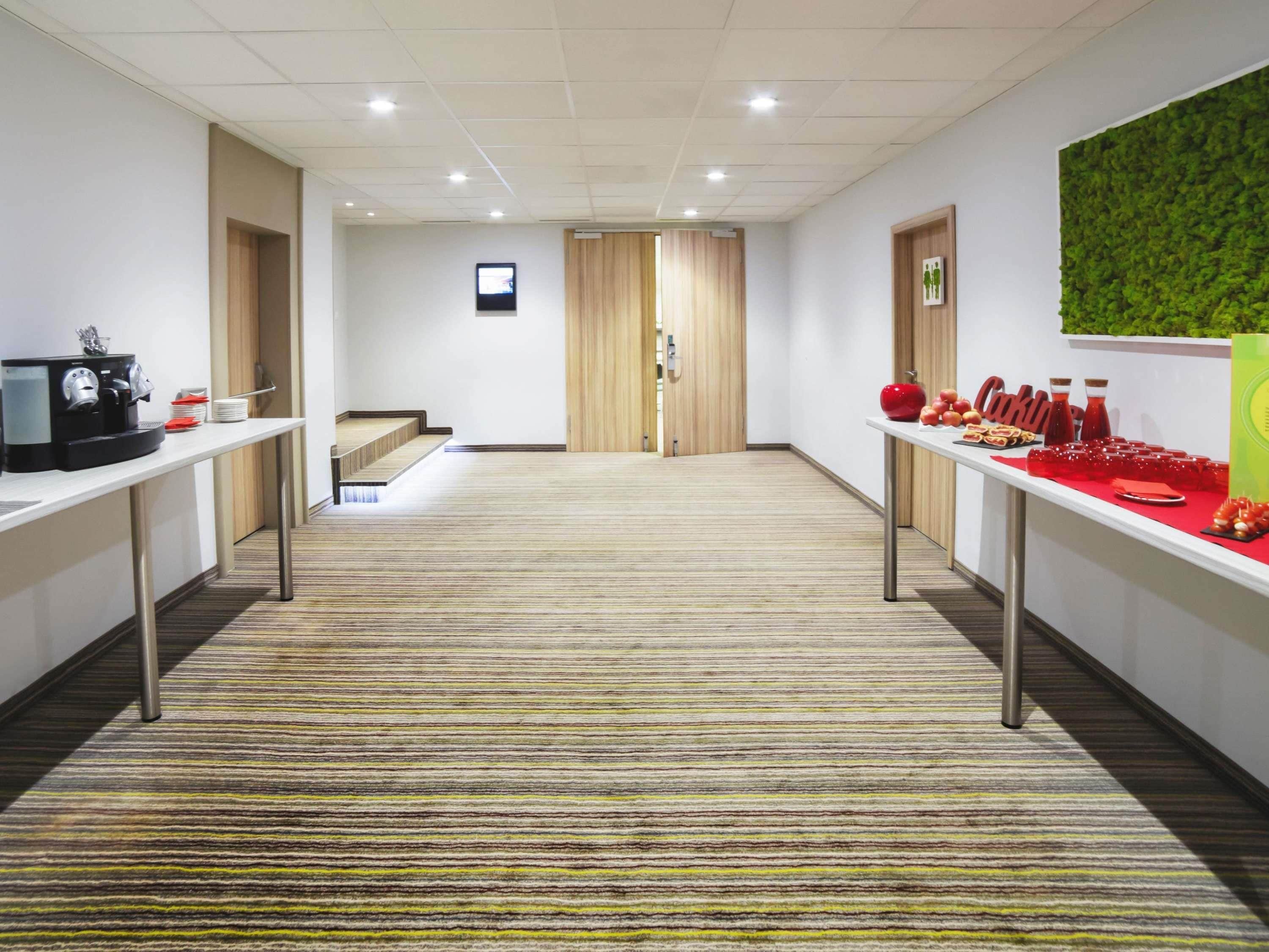 A hotel corridor with a carpeted floor, a coffee machine, and a buffet table with food and drinks.