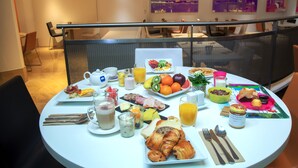 A breakfast table with various food items, drinks, and utensils. - Novotel Geneve Centre (Geneva)