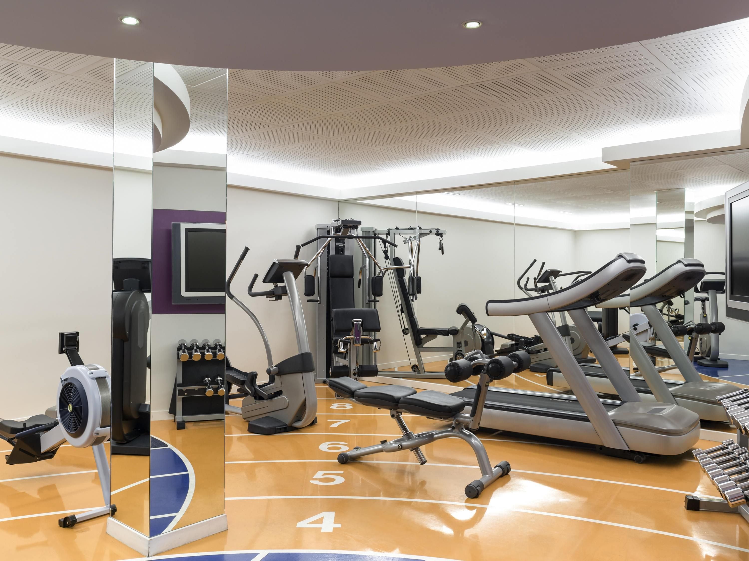 A gym with treadmills, weight machines, and a mirrored wall.