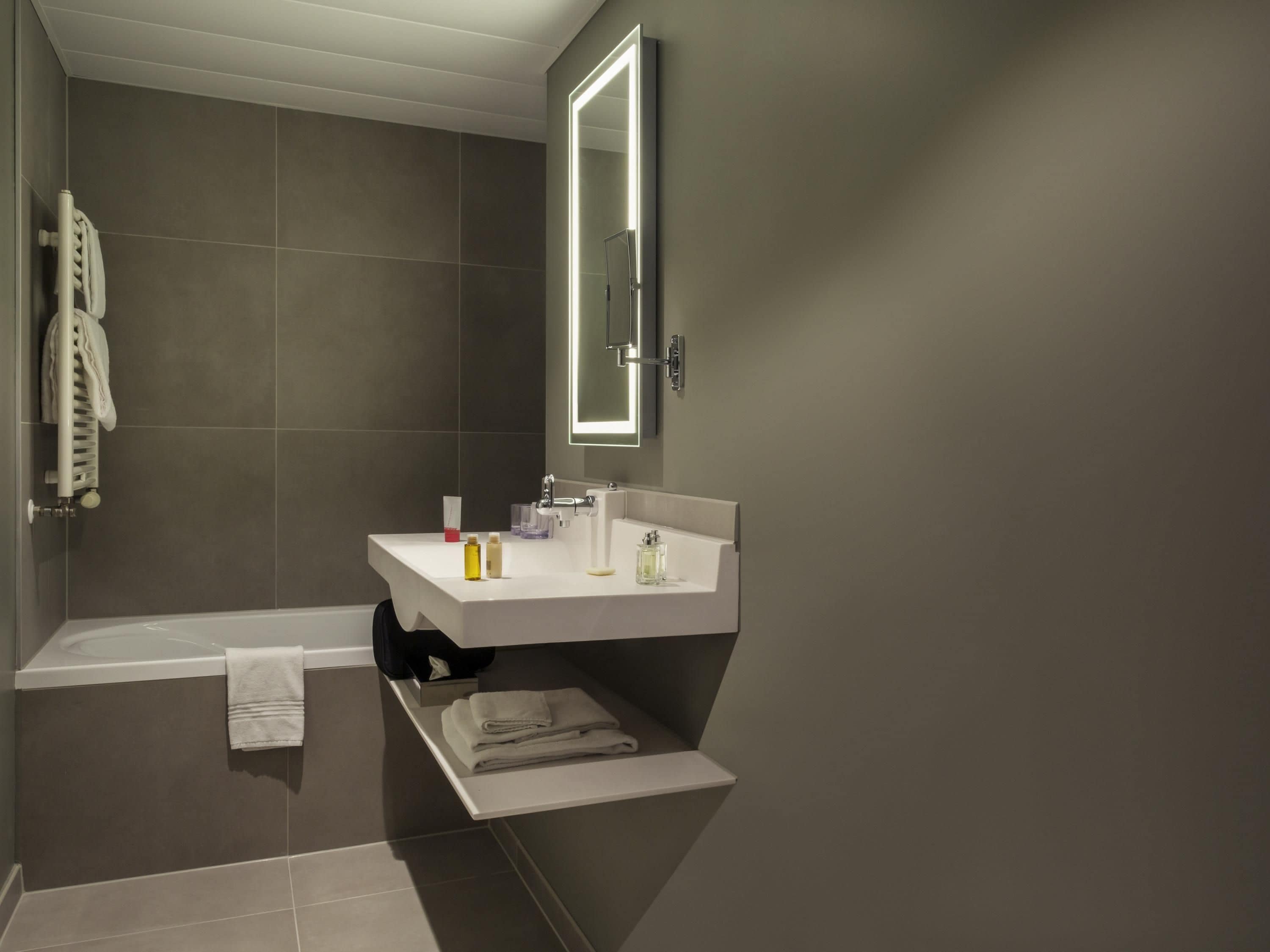 A modern bathroom with a bathtub, a sink, and a mirror.