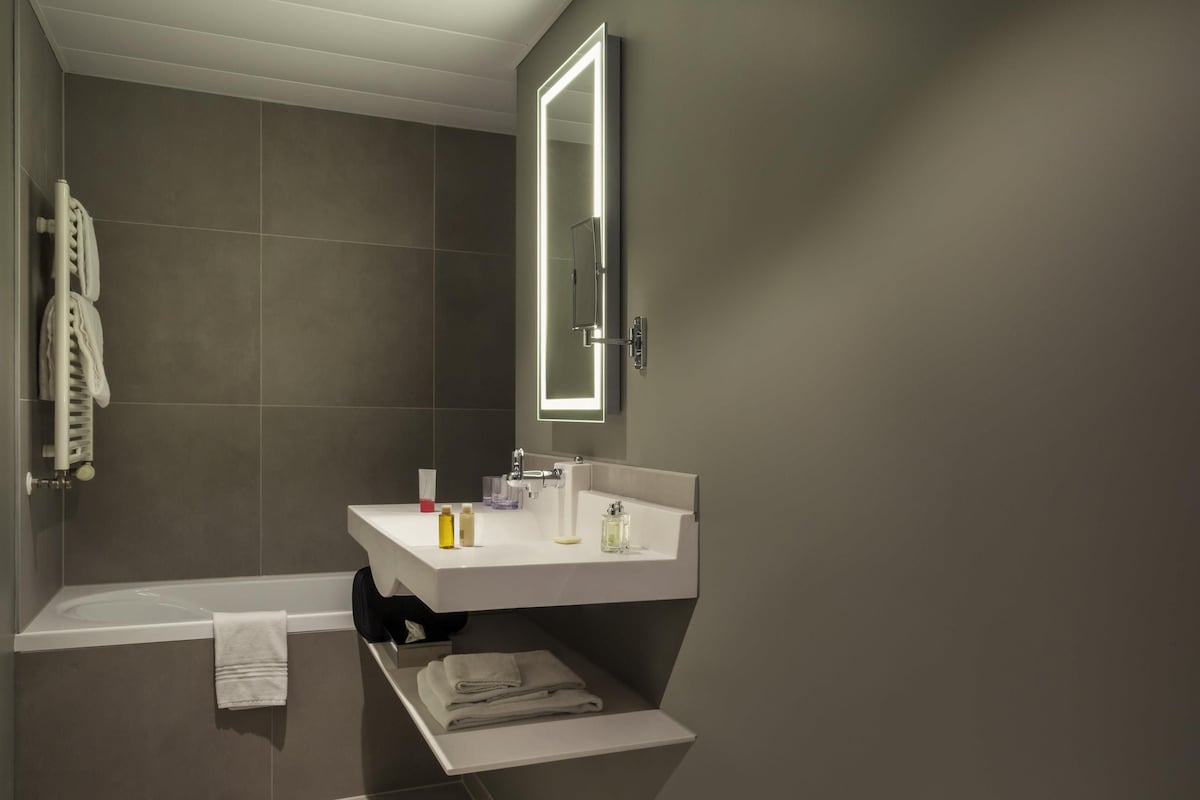 Une salle de bain moderne avec une baignoire, un lavabo et un miroir.
