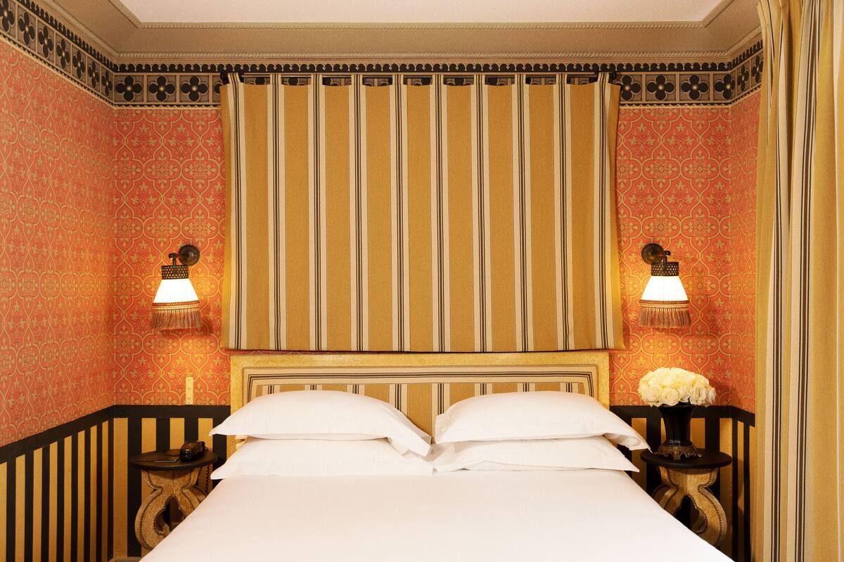 A hotel room with a large bed, two bedside tables with lamps, and a decorative headboard.