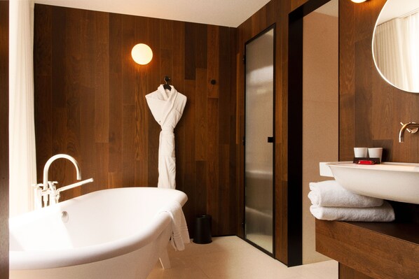 Un baño moderno con una bañera independiente, cabina de ducha con mampara de vidrio y tocador con un espejo grande.