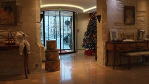 Un hall d’entrée décoré d’un sapin de Noël, doté d’une grande fenêtre et orné d’une statue.