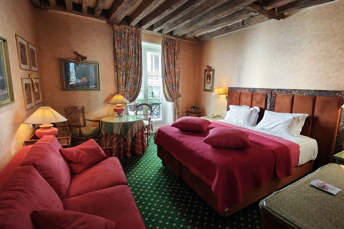 A cozy hotel room with a bed, a sofa, a small table, and a chair.