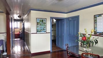 A hallway with wooden floors and blue trim, leading to a dining area with a glass table and chairs.