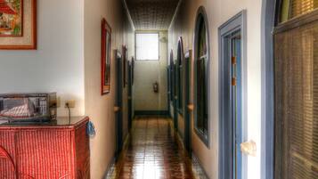 A hallway with patterned floor tiles, a red wicker bench, and a sign reading "SALIDA".