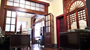 A spacious room with high ceilings, large windows, and wooden furniture.
