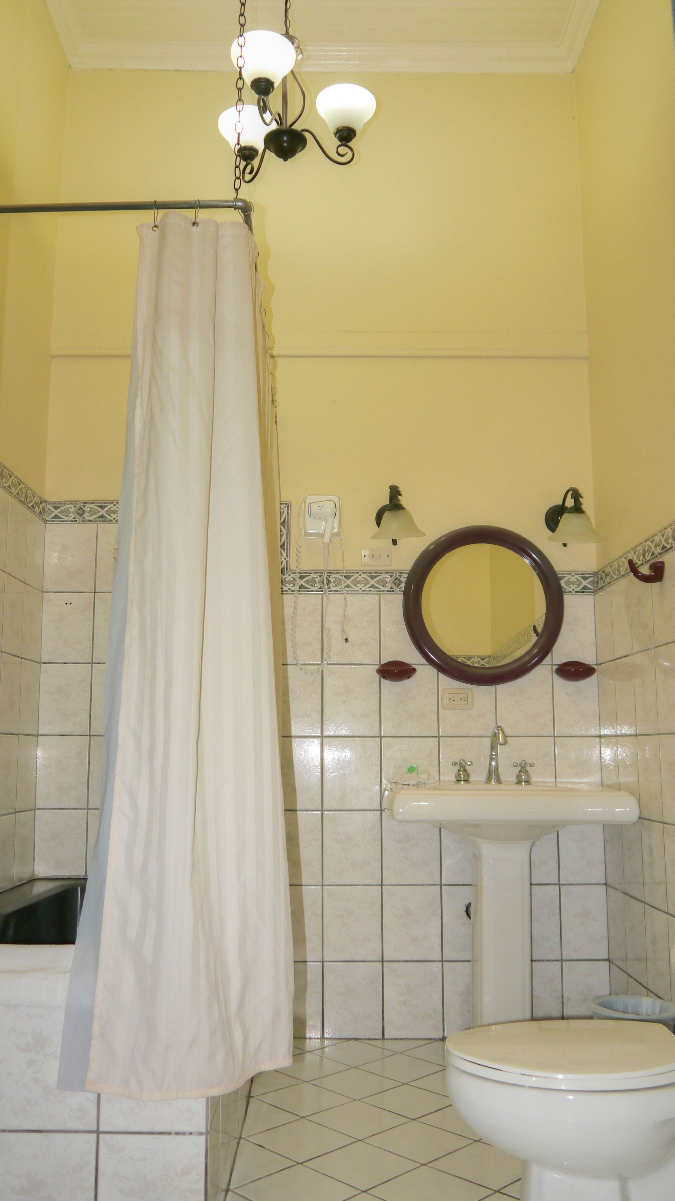 A bathroom with a shower curtain, a sink, a mirror, and a toilet.