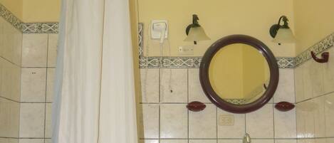 Un baño con cortina de ducha, lavamanos, espejo e inodoro.