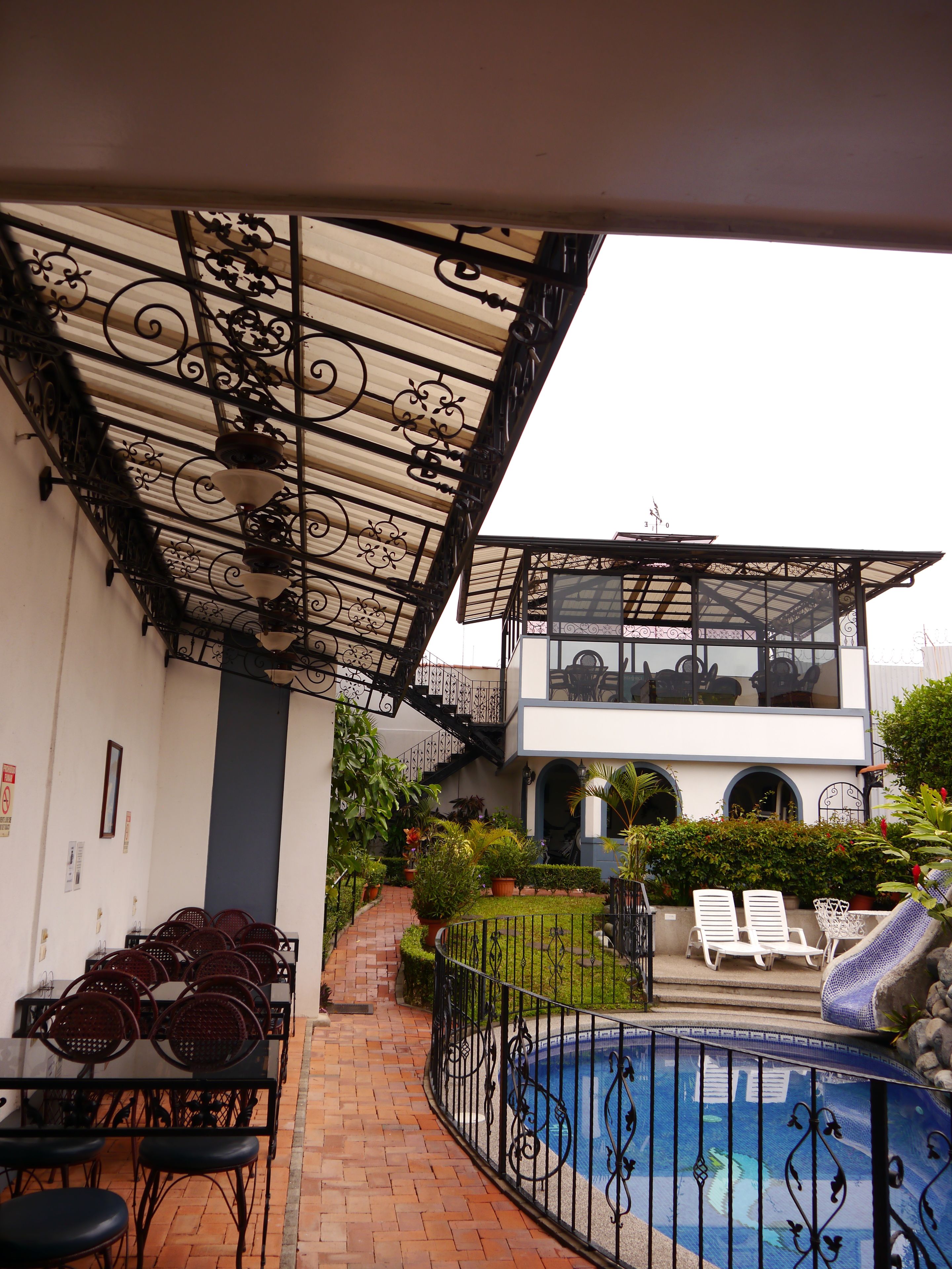 A covered outdoor area with a pool, a staircase, and outdoor seating.