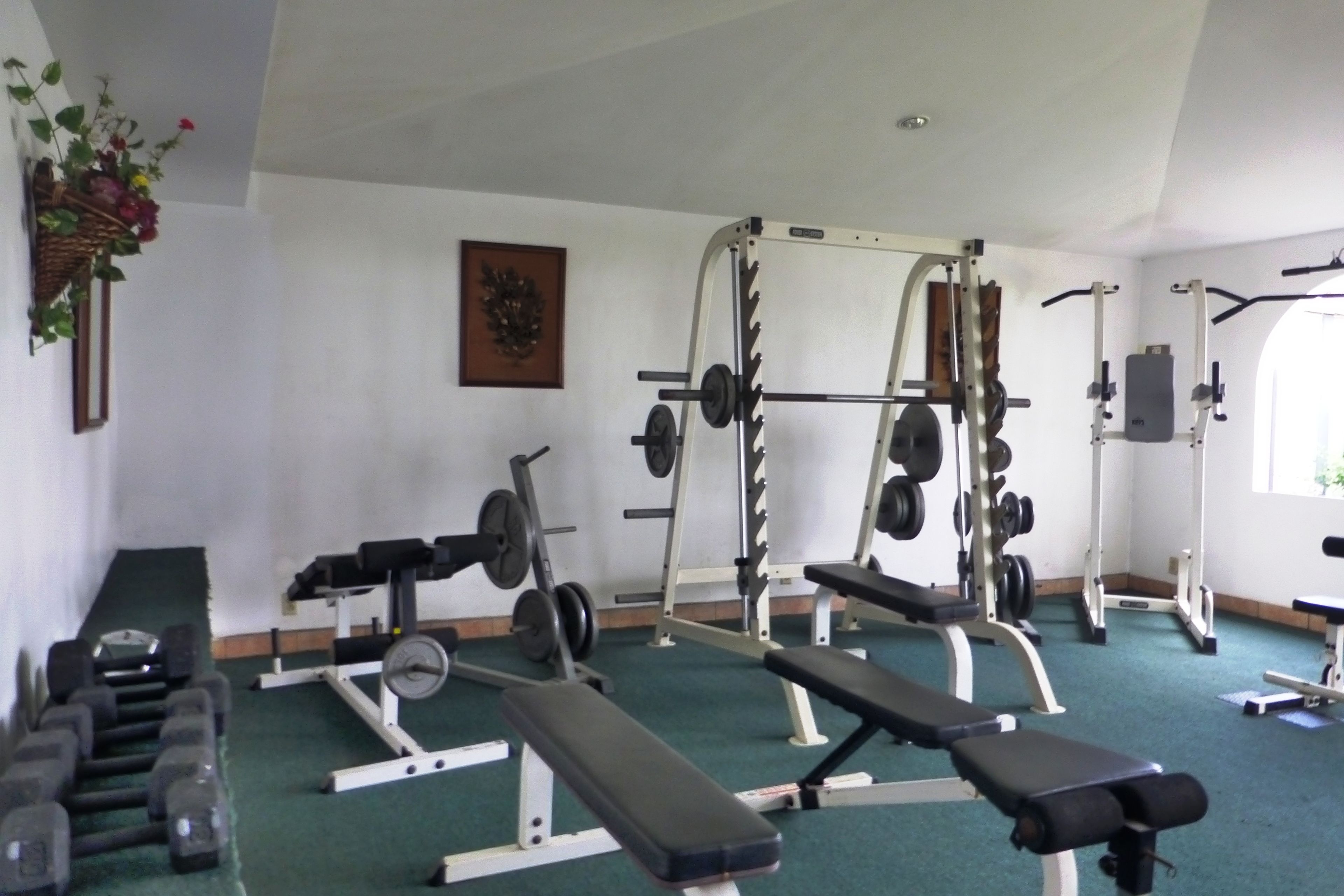 Une salle de sport équipée de bancs, d’haltères et de matériel d’entraînement en musculation.
