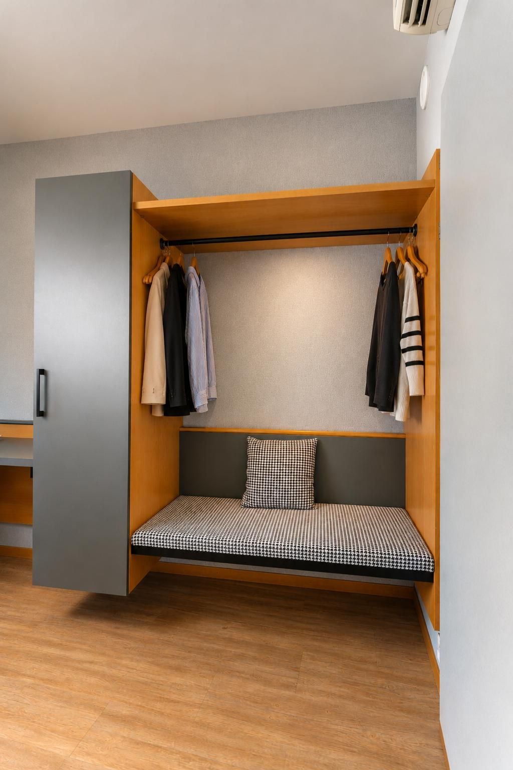 Una habitación compacta con un banco empotrado, armario de madera y perchero.