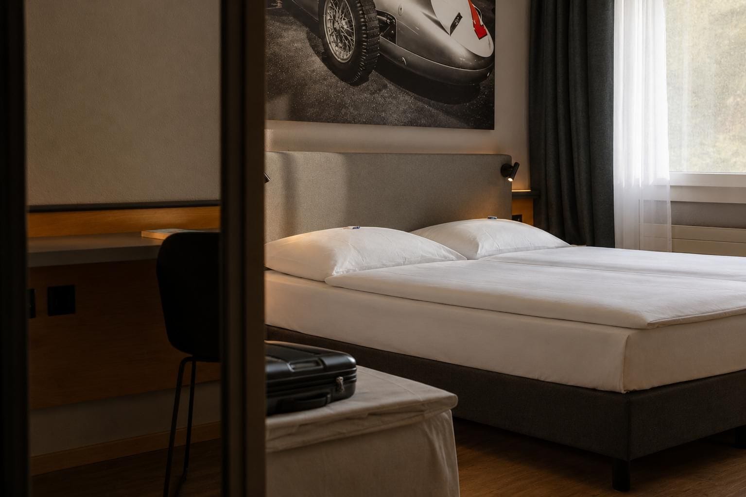 Una habitación de hotel con una cama, un escritorio y una silla.