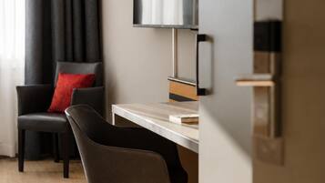 A modern room with a desk, a chair, a television, and a window with curtains.