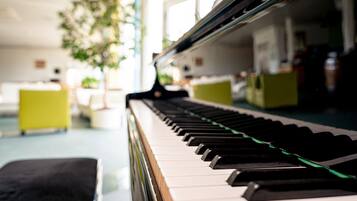 Un piano sur fond flou d’une pièce contenant une plante et des meubles.